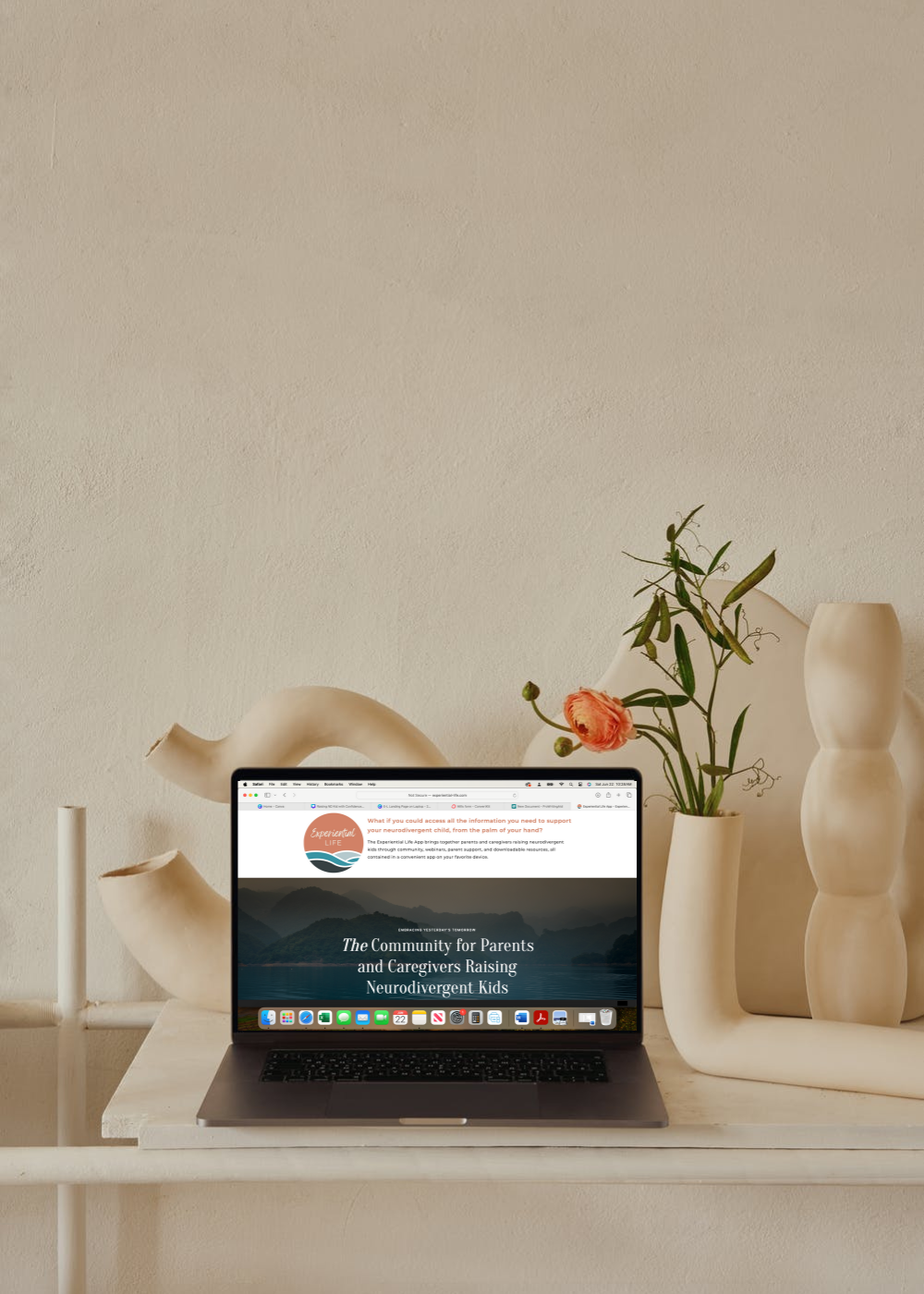 An open laptop sits on a desk. The webpage is open to the Experiential Life website.